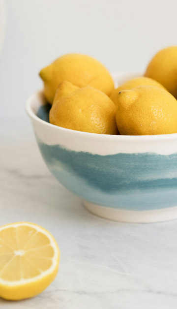 A bowl of lemons on a marble countertop.